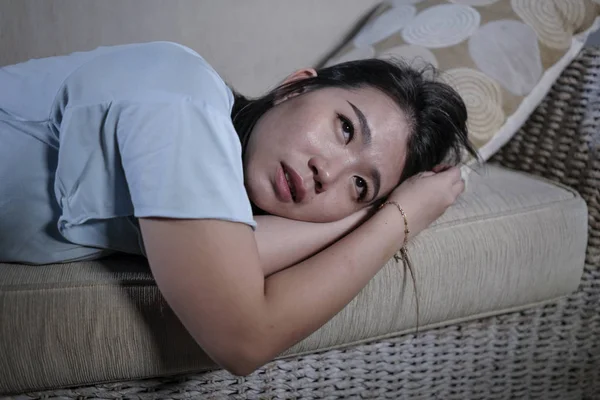 Wanita muda Jepang yang sedih dan tertekan menangis putus asa duduk di sofa rumah menderita masalah depresi dan krisis kecemasan menangis — Stok Foto