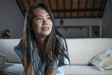evde kanepede genç güzel üzgün ve depresif Asya Japon kadının dramatik yaşam tarzı portre anksiyete krizi ve depresyon sorunu ağlama acı boğulmuş duygu
