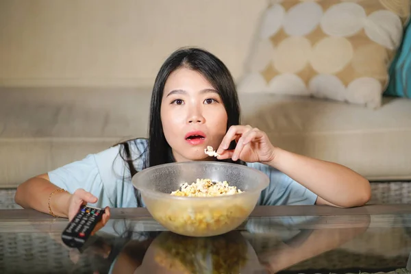 Jeune belle et détendue asiatique chinois regarder drame coréen à la télévision sur triste film romantique manger pop-corn à la maison salon canapé concentré — Photo