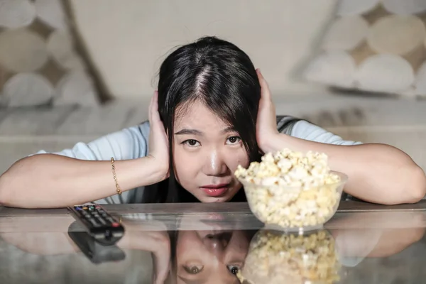Jeune belle et détendue asiatique chinois regarder drame coréen à la télévision sur triste film romantique manger pop-corn à la maison salon canapé concentré — Photo