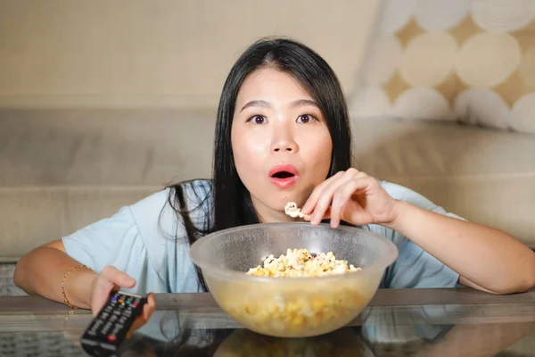 Jeune belle et détendue asiatique japonais femme regarder coréen drame à la télévision sur triste romantique film manger pop-corn à la maison salon canapé concentré — Photo