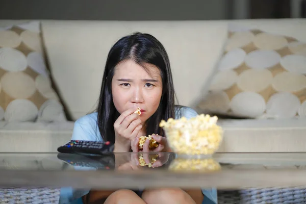 Jeune belle et détendue asiatique japonais femme regarder coréen drame à la télévision sur triste romantique film manger pop-corn à la maison salon canapé concentré — Photo
