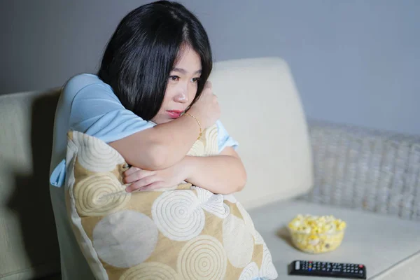 Jeune belle et effrayée asiatique chinois adolescent femme dans la peur regarder film d'horreur effrayant à la maison canapé manger bol de maïs soufflé tenant télécommande — Photo