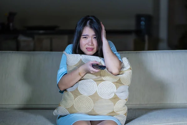 Jovem bonito e assustado asiático japonês adolescente mulher com medo assistindo horror assustador filme em casa sofá comer pipoca tigela segurando controle remoto — Fotografia de Stock