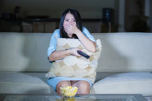 Joven hermosa y asustada asiático coreano adolescente mujer en miedo viendo horror miedo película en casa sofá sofá comer palomitas de maíz bowl holding remote controller — Foto de Stock