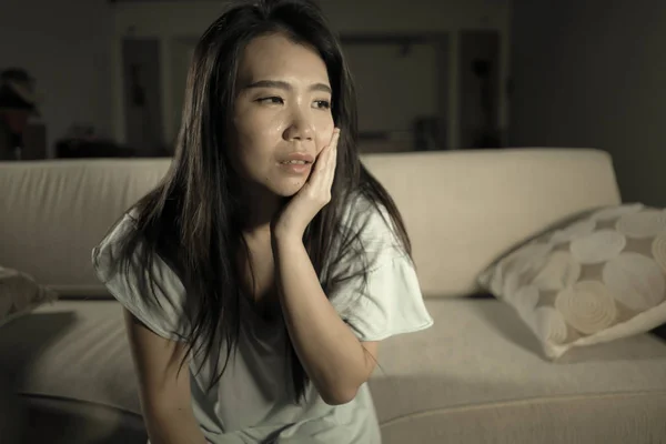 Young beautiful sad and depressed Asian Japanese woman at home sofa couch feeling overwhelmed suffering anxiety crisis and depression problem crying — Stock Photo, Image