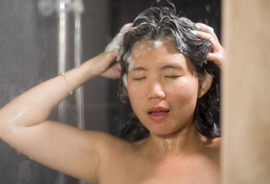 genç güzel ve mutlu Asyalı Koreli kadın 20'li yaşlardan 30'lu yaşlara ıslak ve taze gülümseyen neşeli bir duş alarak saçlarını şampuan ile rahat duygu