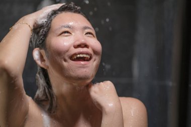 genç güzel ve mutlu Asyalı Çinli kadın 20'li yaşlarda niçin ıslak ve taze gülümseyen neşeli bir duş alarak saçlarını şampuan ile rahat duygu