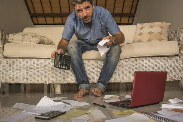 frustrated man at home living room couch doing domestic accounting overwhelmed and worried suffering financial problem going over taxes and payments paperwork