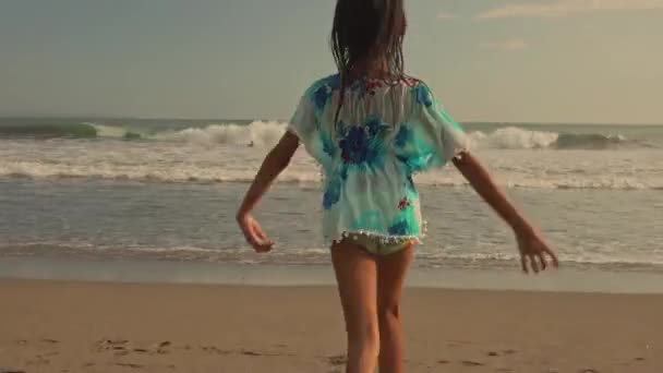 Gimbal 稳定摄像头跟踪序列 岁美丽和快乐的亚洲 印度尼西亚女孩无忧无虑地运行在海滩上享受暑假在异国情调的岛屿日落乐趣 — 图库视频影像