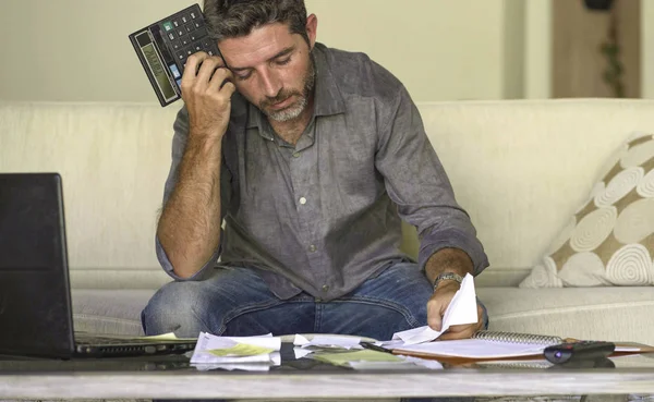 Stressed and desperate man at home living room couch doing domestic accounting with paperwork and calculator feeling overwhelmed and worried suffering financial crisis — Stock Photo, Image