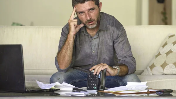 Stressed and desperate man at home living room couch doing domestic accounting with paperwork and calculator feeling overwhelmed and worried suffering financial crisis — Stock Photo, Image