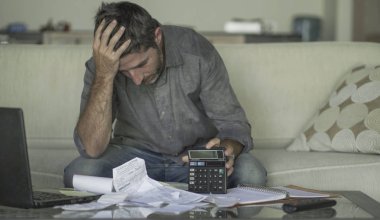 stresli ve umutsuz adam evde oturma odası kanepede evrak ve hesap makinesi duygu ile iç muhasebe yapıyor boğulmuş ve endişeli acı mali kriz 