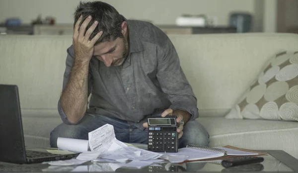 自宅のリビングルームのソファでストレスと絶望的な男は、書類や電卓の感覚で国内会計を行う圧倒され、苦しむ金融危機を心配 — ストック写真