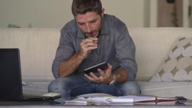 modern dairede iç finans gelir ve vergi evrak sayma hesap makinesi kullanarak oturma odası kanepe kanepe de genç çekici ve meşgul adam muhasebe aylık giderleri ve borç ödemeleri