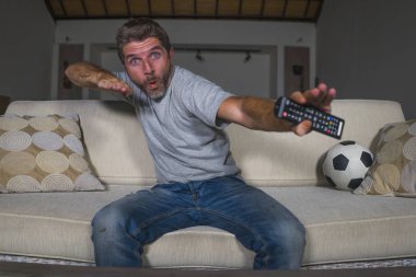 30s veya 40s futbol fan adam futbol oyunu izlerken takım gol deli mutlu çığlık tezahürat tezahürat ev oturma odası kanepede gesturing oturan