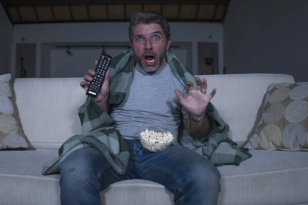 害怕和有趣的人独自在晚上在客厅沙发上看恐怖恐怖电影在电视尖叫和吃爆米花覆盖与毯子 — 图库照片