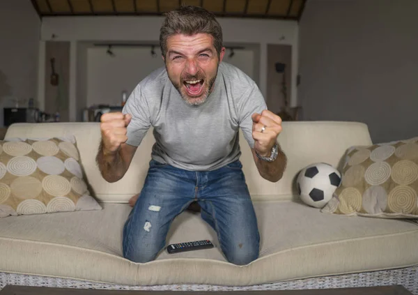 30s o 40s fanático del fútbol hombre viendo partido de fútbol celebrando su equipo anotando gol loco feliz gritando animando a su equipo sentado en casa sala de estar sofá gesto — Foto de Stock