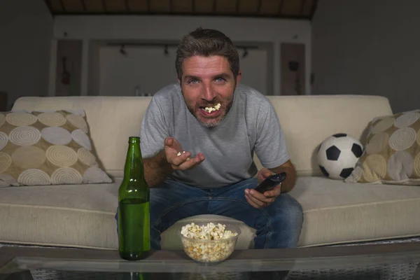 Attrayant supporter de football nerveux et excité homme regardant match de football à la télévision à la maison canapé dans le stress et l'émotion manger du maïs soufflé et boire de la bière — Photo