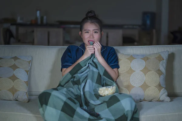 Junge schöne verängstigte und verängstigte asiatische Japanerin, die Horror-Gruselfilm oder Thriller anschaut und in Angst Popcorn isst Gesichtsausdruck Popcorn auf der Couch isst — Stockfoto