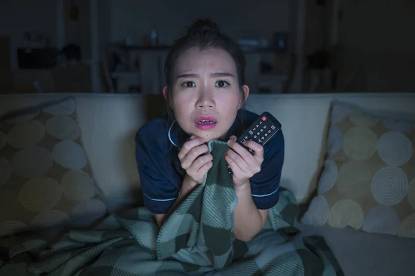Jeune belle effrayé et effrayé asiatique japonais femme regarder horreur effrayant film ou thriller manger pop-corn dans la peur expression du visage manger pop-corn sur canapé — Photo