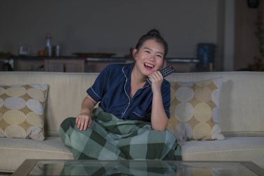 genç güzel mutlu ve neşeli Asyalı Çinli kadın Tv komedi filmi veya komik göstermek gülerek izlerken ve battaniye ile evde kanepede oturan patlamış mısır yeme 
