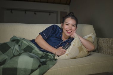 genç güzel mutlu ve neşeli Asyalı Japon kadın Tv komedi filmi veya komik göstermek gülerek ve battaniye ile evde kanepede oturan patlamış mısır yeme izlerken
