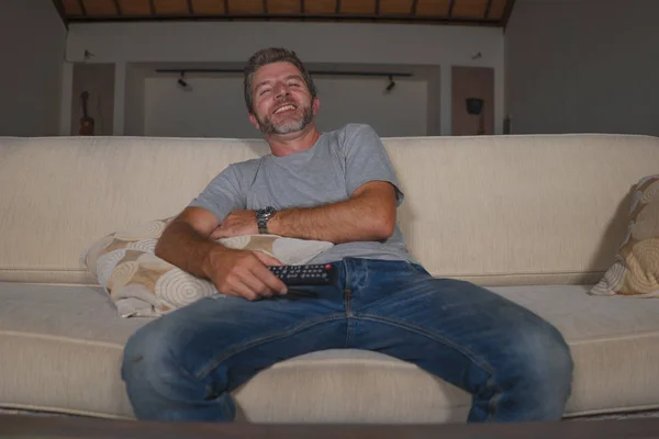 Casa estilo de vida retrato de jovem homem feliz e atraente assistindo televisão show de quadrinhos ou filme de comédia rindo animado e relaxado sentado no sofá da sala de estar — Fotografia de Stock