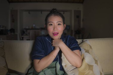 genç güzel mutlu ve rahat Asyalı Çinli kadın evde oturma odasında kanepede rahat oturan Tv show bölüm veya romantik komedi filmi tatlı gülümseyen izlerken