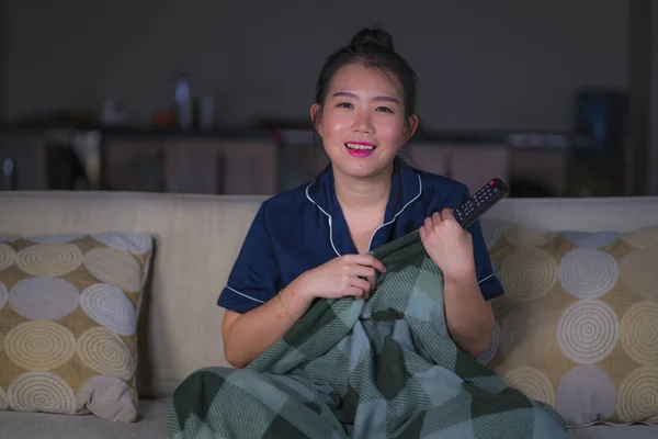 Молодая красивая счастливая и расслабленная азиатская китаянка у себя дома сидит уютно на диване смотреть эпизод телешоу или романтический комедийный фильм улыбаясь сладкий — стоковое фото