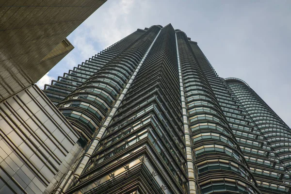 Vista de baixo ângulo da deslumbrante Torre Petronas refletindo o sol na fachada metálica isolada em um céu azul na Malásia — Fotografia de Stock