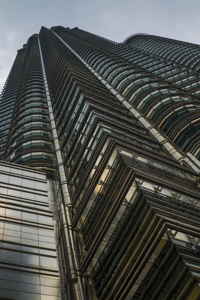 Vista de baixo ângulo da deslumbrante Torre Petronas refletindo o sol na fachada metálica isolada em um céu azul na Malásia — Fotografia de Stock