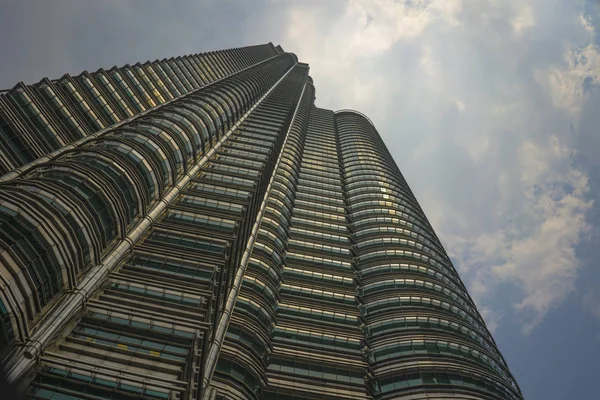 Низкий угол обзора ошеломляющей башни Петронас, отражающей солнце в металлическом фасаде, изолированном на голубом небе в Малайзии — стоковое фото