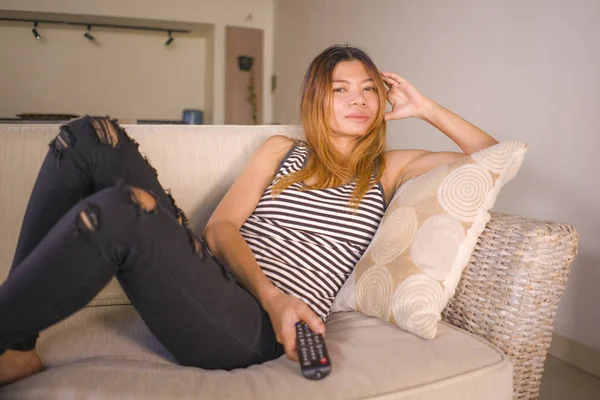 Genç çekici ve rahat Asya Endonezyalı kadın TV uzaktan izlerken televizyon film veya dizi bölüm oturma odası kanepede rahat yalan zevk — Stok fotoğraf