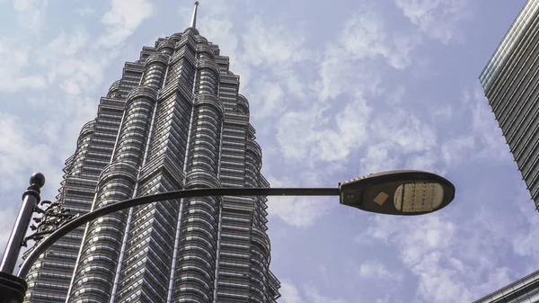 Bela vista da deslumbrante Torre Petronas emergente majestosa sobre edifícios de escritórios distritais KLCC em um dia ensolarado — Fotografia de Stock
