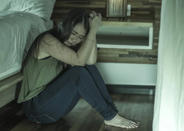 young depressed and sad Asian Korean woman sitting on floor at bedroom next to bed suffering depression problem and anxiety crisis feeling desperate