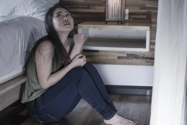 Mladá, deprimovaná a smutná Asijská Japonská žena, sedící na podlaze v ložnici u postele trpící potížemi s depresí a úzkostnou krizí, pocitem zoufalé — Stock fotografie