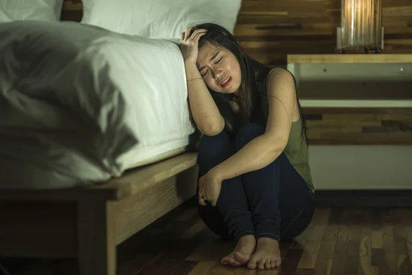 Drammatico ritratto stile di vita di giovane donna cinese asiatica depressa e triste seduta sul pavimento della camera da letto accanto al letto che soffre di depressione problema e crisi di ansia — Foto Stock