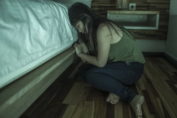 Dramatisches Lebensstil-Porträt einer jungen depressiven und traurigen asiatischen Chinesin, die im Schlafzimmer neben dem Bett auf dem Boden sitzt und unter Depressionen und Angstzuständen leidet — Stockfoto