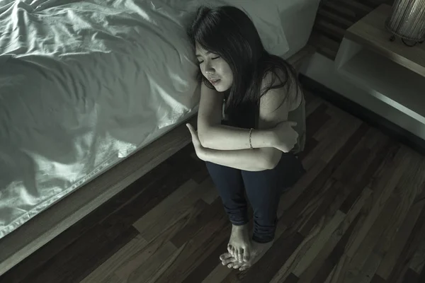 Dramático estilo de vida retrato de la joven deprimida y triste mujer china asiática sentada en el suelo en el dormitorio al lado de la cama sufriendo depresión problema y crisis de ansiedad —  Fotos de Stock