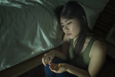 genç güzel umutsuz ve boşa bağımlısı Asyalı Koreli kadın evde yatak odası katta uyuşturucu aşırı doz alarak hasta ve depresif acı depresyon hissi