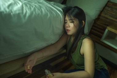genç güzel umutsuz ve boşa bağımlısı Asyalı Koreli kadın evde yatak odası katta uyuşturucu aşırı doz alarak hasta ve depresif acı depresyon hissi
