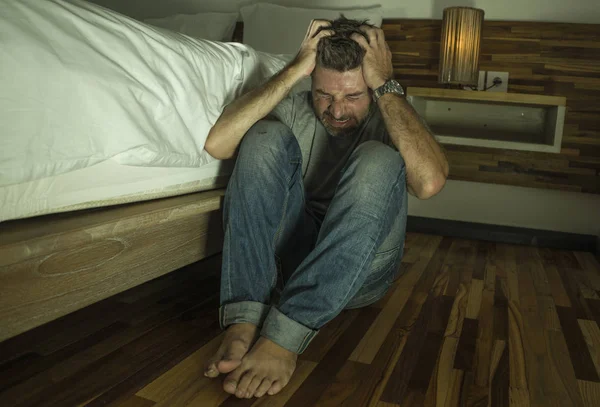 Dramatisches Porträt eines jungen verzweifelten und depressiven einsamen Mannes, der auf dem Schlafzimmerboden sitzt und weint, während er unter Angstkrise und Depressionsproblemen leidet und sich hilflos fühlt — Stockfoto
