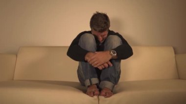 Yavaş zoom genç çekici depresif ve üzgün gölgeli adam dramatik çekim evde kanepede ağlayarak ağrı ve umutsuzluk anksiyete krizi ve depresyon sorunu acı kayıp 