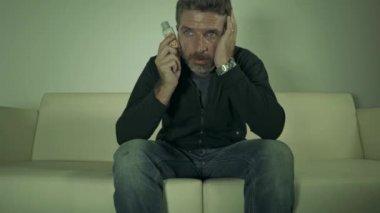 aşırı dozda ilaç kötüye ev kanepesinde oturan antidepresan tablet şişe tutan genç çekici depresif ve boşa hap bağımlısı adam dramatik portre