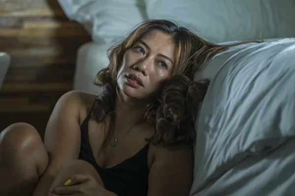 Junge schöne traurige und deprimierte asiatische indonesische Frau im Nachthemd auf dem Schlafzimmerboden neben dem Bett fühlt sich gebrochen und verloren leiden Depressionen und Angst — Stockfoto