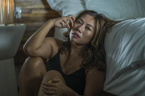 Junge schöne traurige und deprimierte asiatische indonesische Frau im Nachthemd auf dem Schlafzimmerboden neben dem Bett fühlt sich gebrochen und verloren leiden Depressionen und Angst — Stockfoto