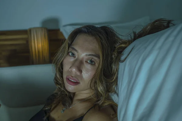 Jonge mooie trieste en depressieve Aziatische Indonesische vrouw in nachthemd op slaapkamer verdieping door het bed gevoel gebroken en verloren lijden depressie en angst — Stockfoto