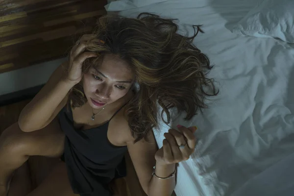 Giovane bella triste e depressa asiatica donna indonesiana in camicia da notte sul pavimento della camera da letto dal letto sensazione di rottura e perdita di sofferenza depressione e ansia — Foto Stock