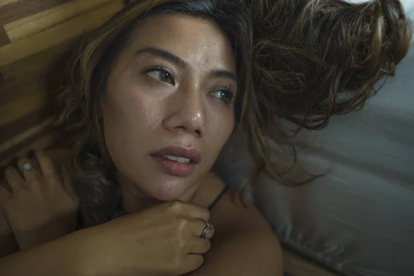 Young beautiful sad and depressed Asian Indonesian woman in nightgown on bedroom floor by the bed feeling broken and lost suffering depression and anxiety — Stock Photo, Image